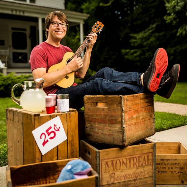 Photo of Justin Roberts playing a Ukelele at a staged Lemonade Stand. Photo credit: Todd Rosenberg